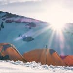three yellow and red dome tents on snow capped mountain