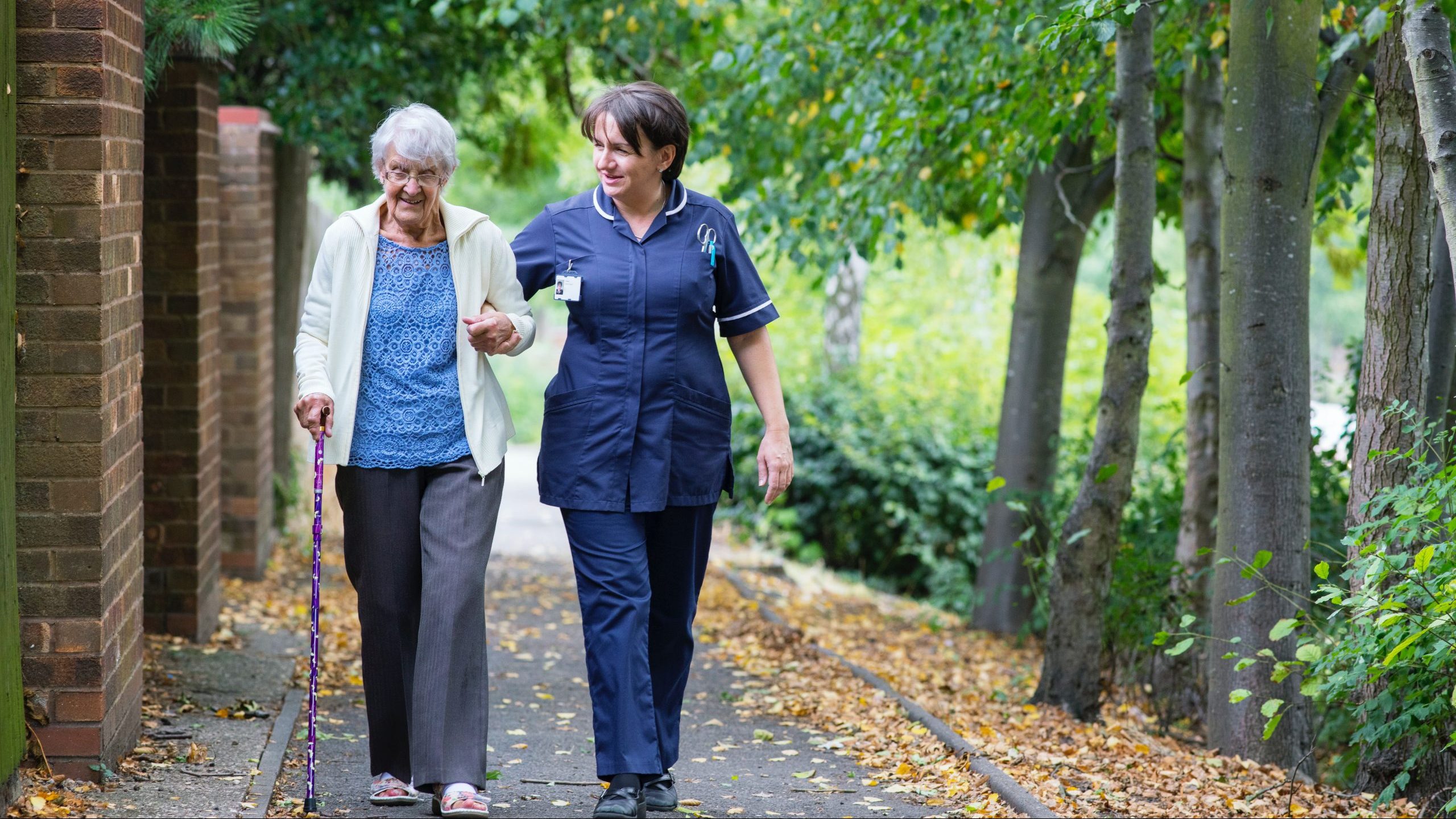 man in blue polo shirt and woman in white dress walking on pathway