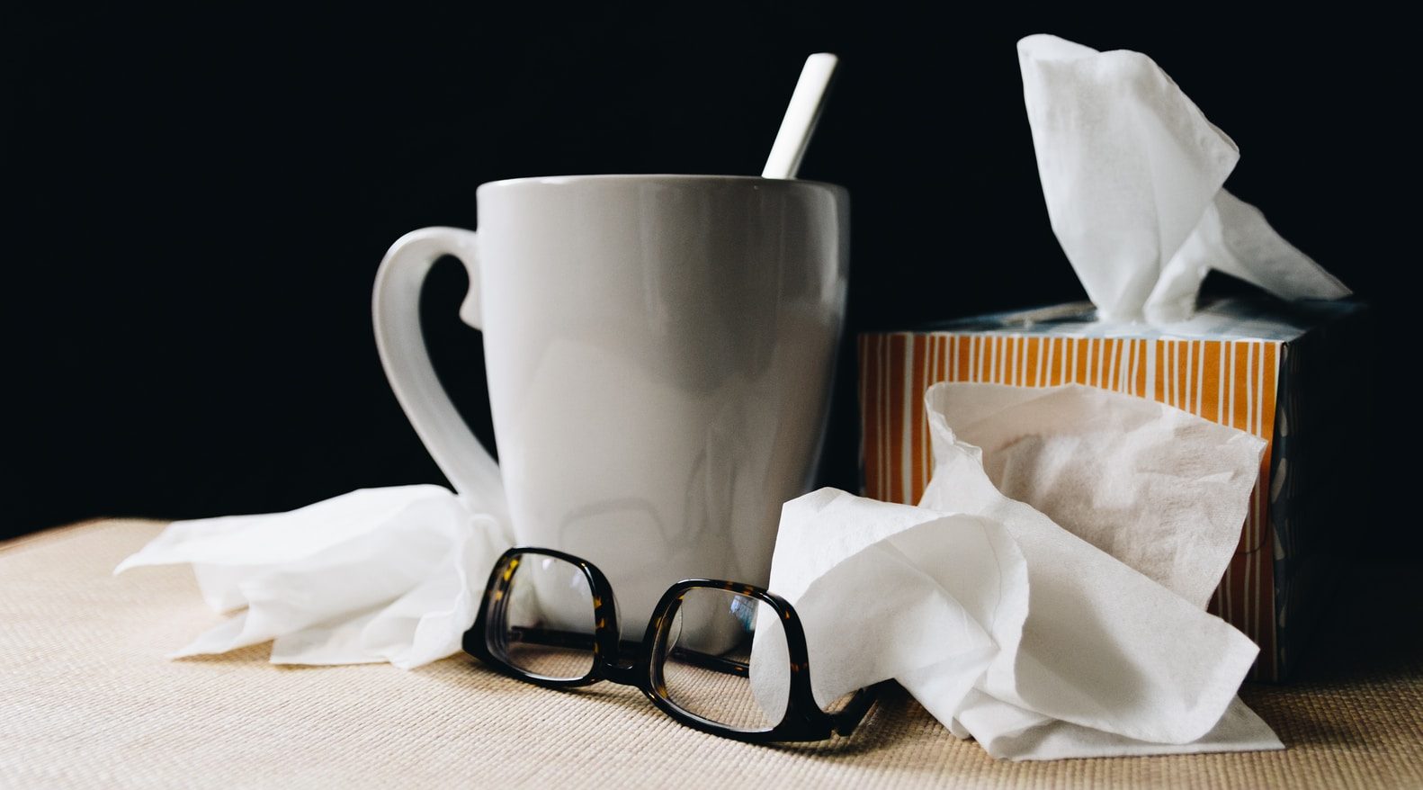 white ceramic mug on white table beside black eyeglasses