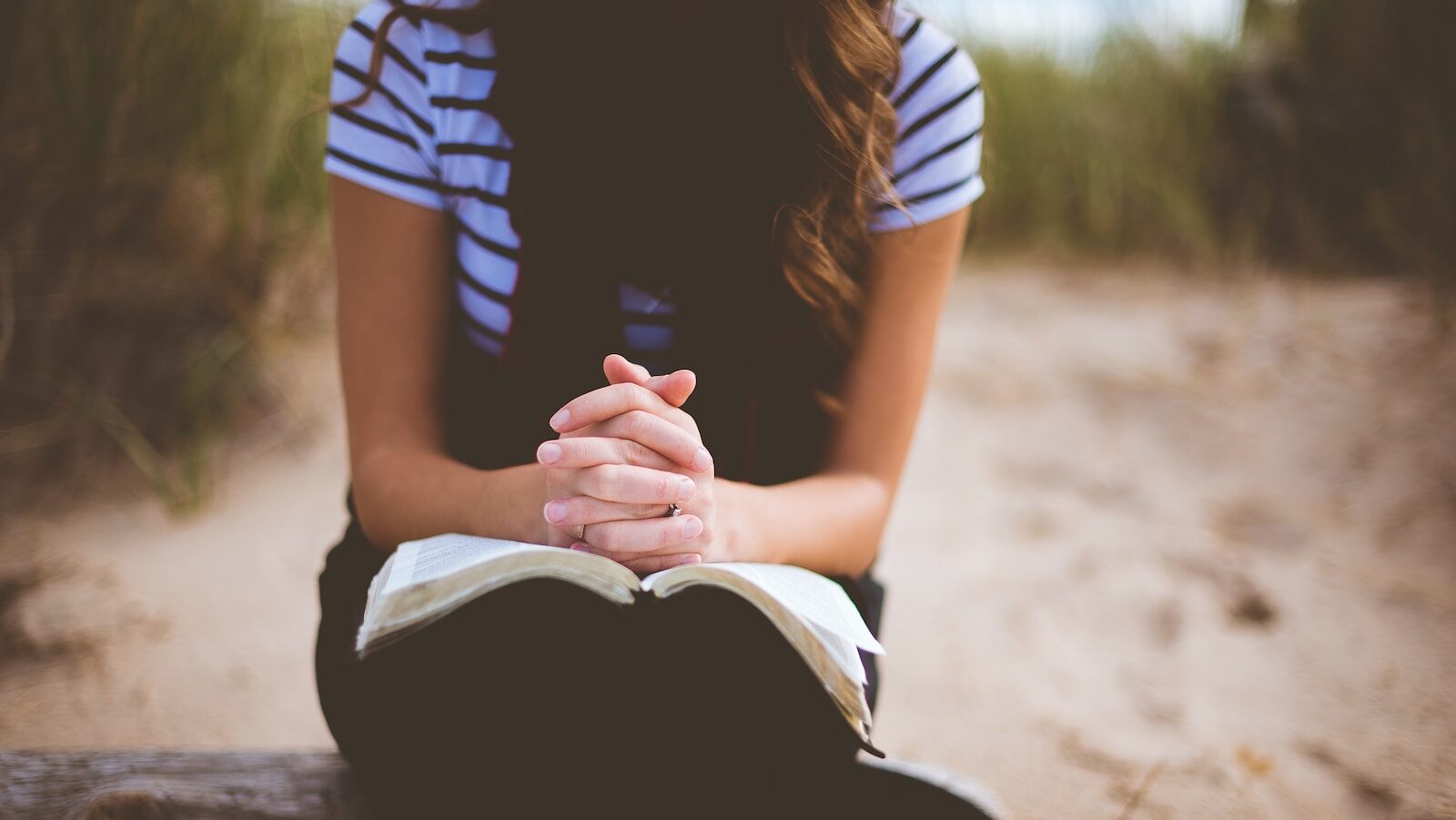 woman sitting on brown bench while reading book