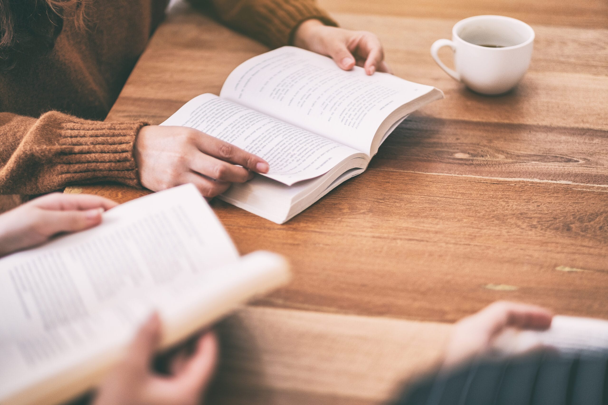 Group of people sitting and enjoyed reading books together on wooden table