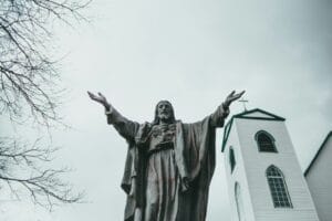 man in coat holding stick statue