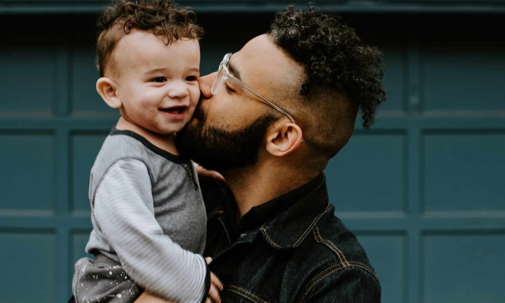 Photo by Kelly Sikkema man carrying baby boy and kissing on cheek