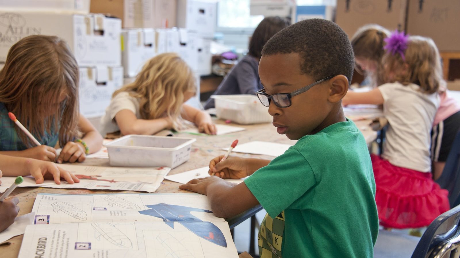 Photo by CDC boy in green sweater writing on white paper
