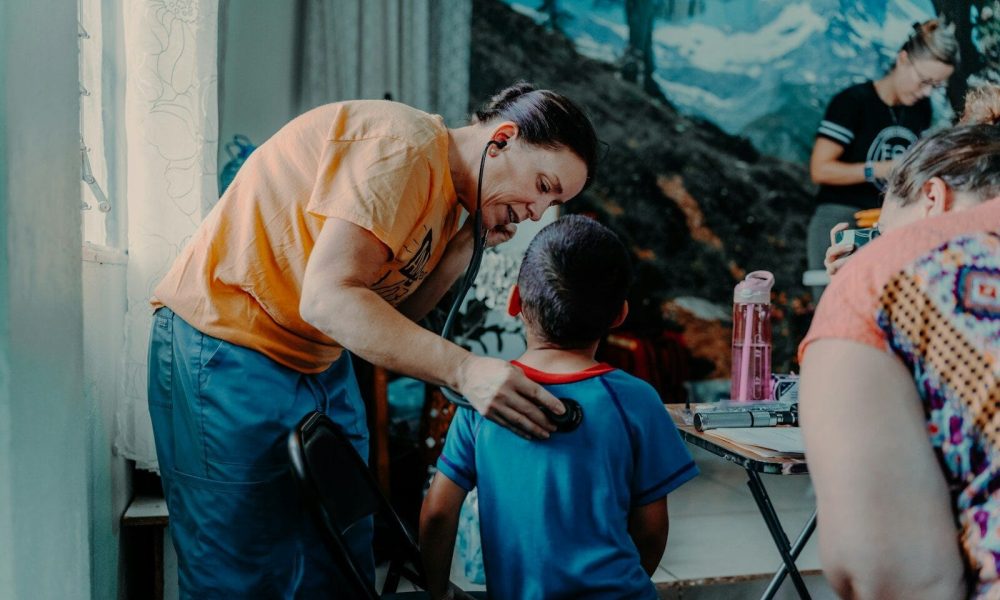 a man standing over a little boy who is sitting at a table